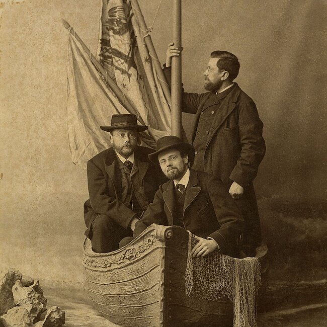 Atelieraufnahme von Ferdinand Österreicher, Peter Rosegger und Josef Wichner im Kahn sitzend.